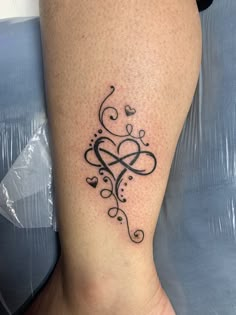 a tattoo on the leg of a woman with hearts and swirls in black ink