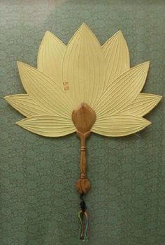 a wooden spoon hanging from the side of a wall with a flower design on it