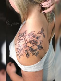 the back of a woman's shoulder with flowers and leaves tattooed on her chest