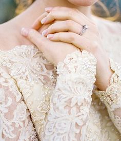 a woman in a white dress is holding her hand on her chest and looking off to the side