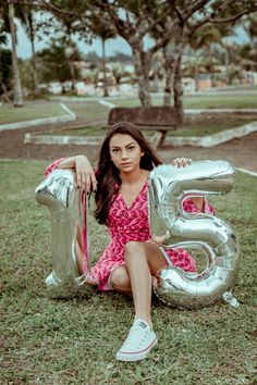 a woman sitting on the ground with an inflatable number 5 balloon next to her