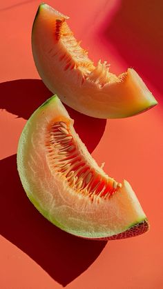 two pieces of melon sitting on top of a red surface