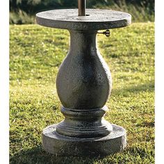 an umbrella is placed on top of a pedestal in the grass