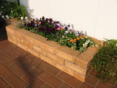 a brick planter filled with lots of flowers