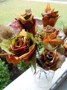 a vase filled with lots of flowers sitting on top of a window sill next to a grass covered field