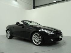 a black sports car is parked in a white room with grey walls and flooring