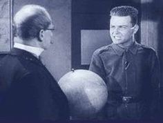 a man in uniform is talking to another man with a globe on his shoulder and wearing glasses