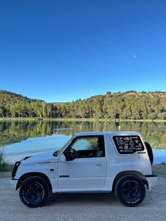 a white truck parked in front of a lake