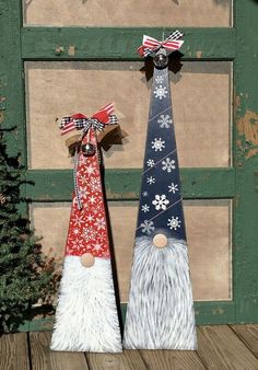 two gnomes are standing next to each other on a wooden deck with snowflakes