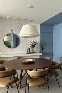 a dining table with six chairs and a round mirror hanging from the wall above it