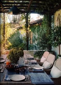 an outdoor dining area with wicker chairs and table set for four, surrounded by greenery