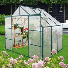 a green house with pink flowers in the yard