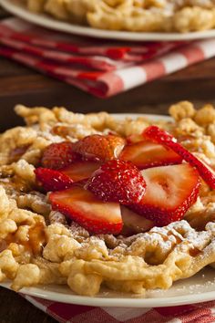 a waffle topped with strawberries on top of a table next to another plate