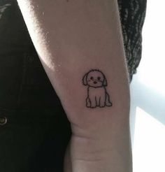 a small black and white dog tattoo on the left inner arm, with an outline of a poodle