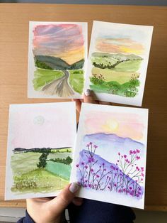 four watercolor paintings are being held up