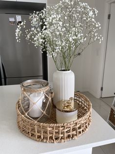 a wicker tray with flowers in it and a candle holder on the counter top