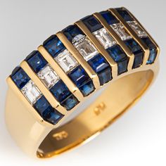 This pretty band ring features a centered row of seven (7) channel set, baguette cut diamonds. The center row is flanked on either side by a row of seven (7) channel set, square step cut sapphires. The faces are each channel set with seven (7) square step sapphires. The ring measures 8.3mm at the top, rises 3.4mm above the finger, tapering to 3.6mm wide and 0.7mm thick at the base of the shank. It is currently a size 6. Luxury Emerald Cut Channel Set Sapphire Ring, Luxury Jewelry With Channel Set Baguette Cut, Luxury Channel Set Ruby Ring For Gift, Luxury Channel Set Ruby Ring Gift, Luxury Diamond Sapphire Ring Channel Set, Channel Set Yellow Gold Sapphire Ring As Gift, Channel Set Sapphire Ring, Channel Set Sapphire Ring Jewelry, Luxury Channel Set Ruby Ring In Yellow Gold