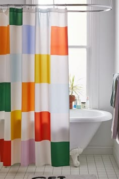 a colorful shower curtain with sunglasses on the floor and a bathtub in the background