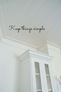 there is a white cabinet with writing on the wall above it that says keep things simple