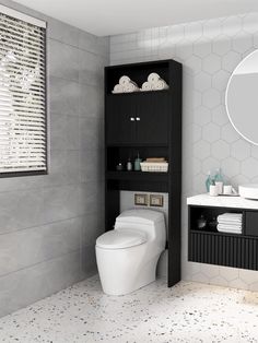 a white toilet sitting in a bathroom next to a black shelf with towels on it