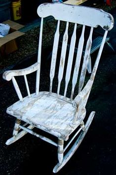 an old white rocking chair sitting on the ground