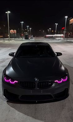 a black car with purple lights on it's hood parked in the street at night