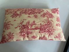 a pink and white pillow with a red toiler design on the front, sitting on a table