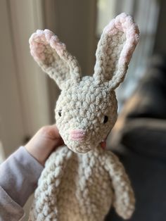 a person holding a small stuffed animal in their left hand and wearing a knitted bunny costume