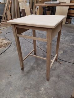 a wooden table sitting on top of a floor next to a pile of wood planks