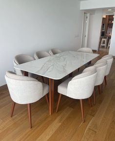 a dining room table with six chairs and a white marble slab top on the center