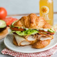 a sandwich sitting on top of a white plate next to a bottle of orange juice