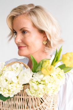 a woman holding a basket with flowers in it