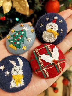 three handmade christmas ornaments sitting on top of a persons palm next to a christmas tree