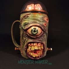 a ceramic mug with an evil face on it's side and eyes painted green