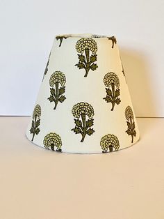 a lamp shade with flowers on it sitting on a white counter top next to a wall