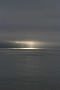 the sun shines through dark clouds over the ocean