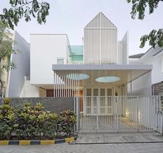 an entrance to a house with white walls and metal gates on the outside, surrounded by greenery