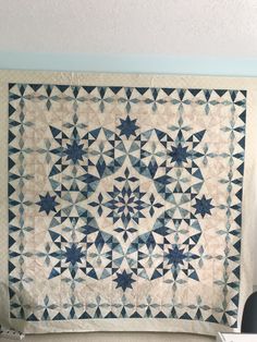 a blue and white quilt hanging on the wall