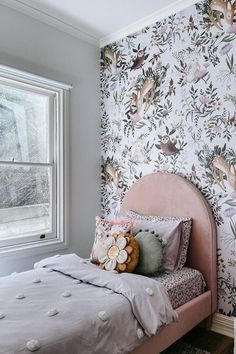 a bedroom with floral wallpaper and a pink bed