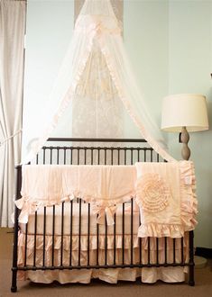 a baby crib in a room with a canopy over the crib and two lamps on either side