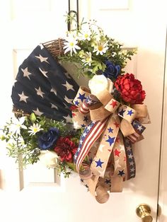 a patriotic wreath with flowers and an umbrella hanging on the front door to welcome visitors