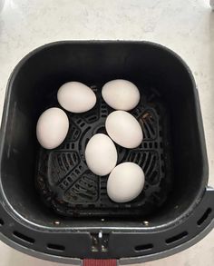 six eggs are in a black basket on the floor