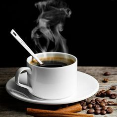 a cup of coffee with steam rising out of it and cinnamons on the side