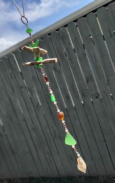 a bird feeder hanging from a chain with sea glass and wood beads on it's side