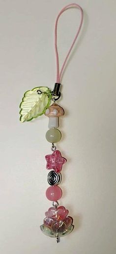 a pink and green necklace hanging on a white wall