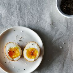 two boiled eggs on a plate with salt and pepper in small bowls next to them