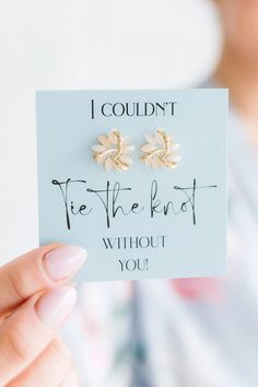 a woman holding up a card with two earrings on it that says i couldn't tie the knot without you