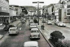 an old black and white photo of cars driving down the street