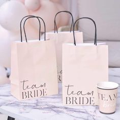 three paper bags with the words team bride on them sitting next to a coffee cup