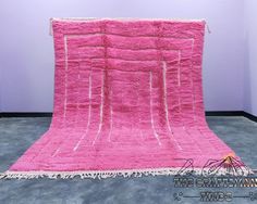 a pink rug with fringes on the floor in front of a white wall and purple walls